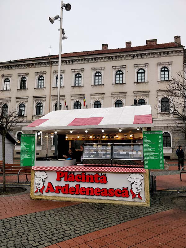 A small food stall in the front, a building in the bacl.