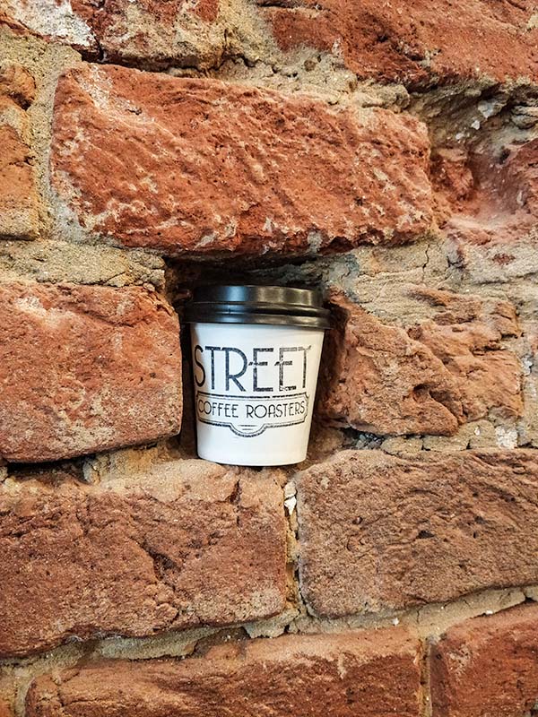 A coffee cup in a whole in the brick wall.