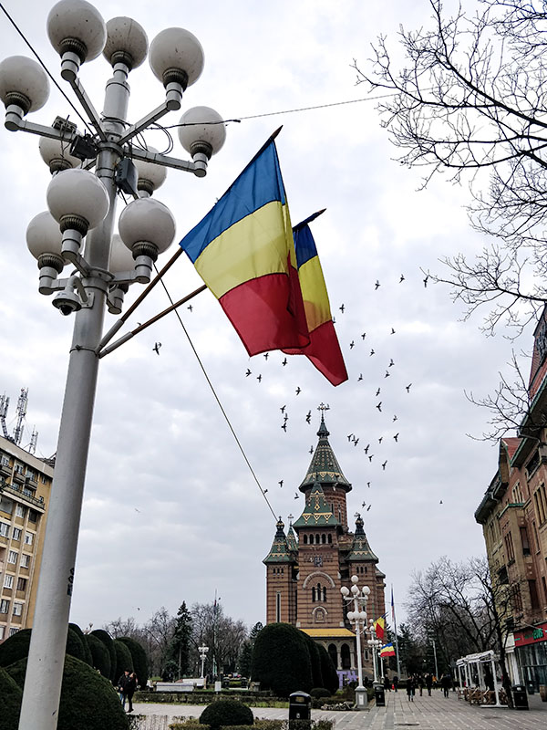 In the front a lantern with two Romanian flags. In the back a orthodox church.