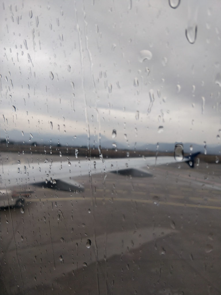 In the front raindrops on a window. In the back a airplane wing.
