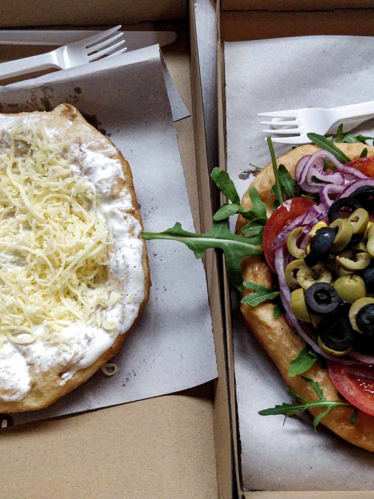Two Hungarian Langos. On the left side a Langos with cheese, on the right side a vegan Langos with veggies.