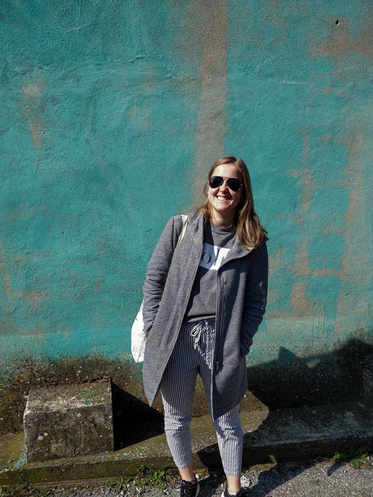 A smiling girl standing in front of a blue wall.