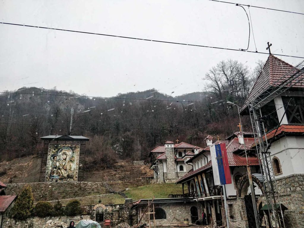 Raindrops on the window, in the back church buildings and a Serbian flag. 