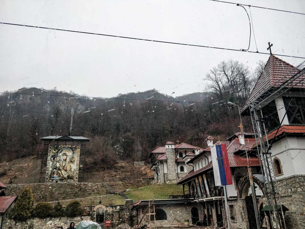 Raindrops on the window, in the back church buildings and a Serbian flag.