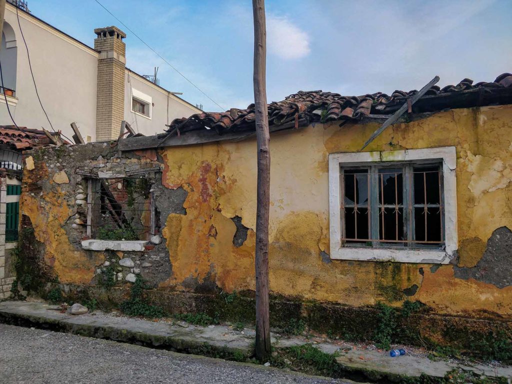 An old, yellow building that is slowly disintegrating in its parts.