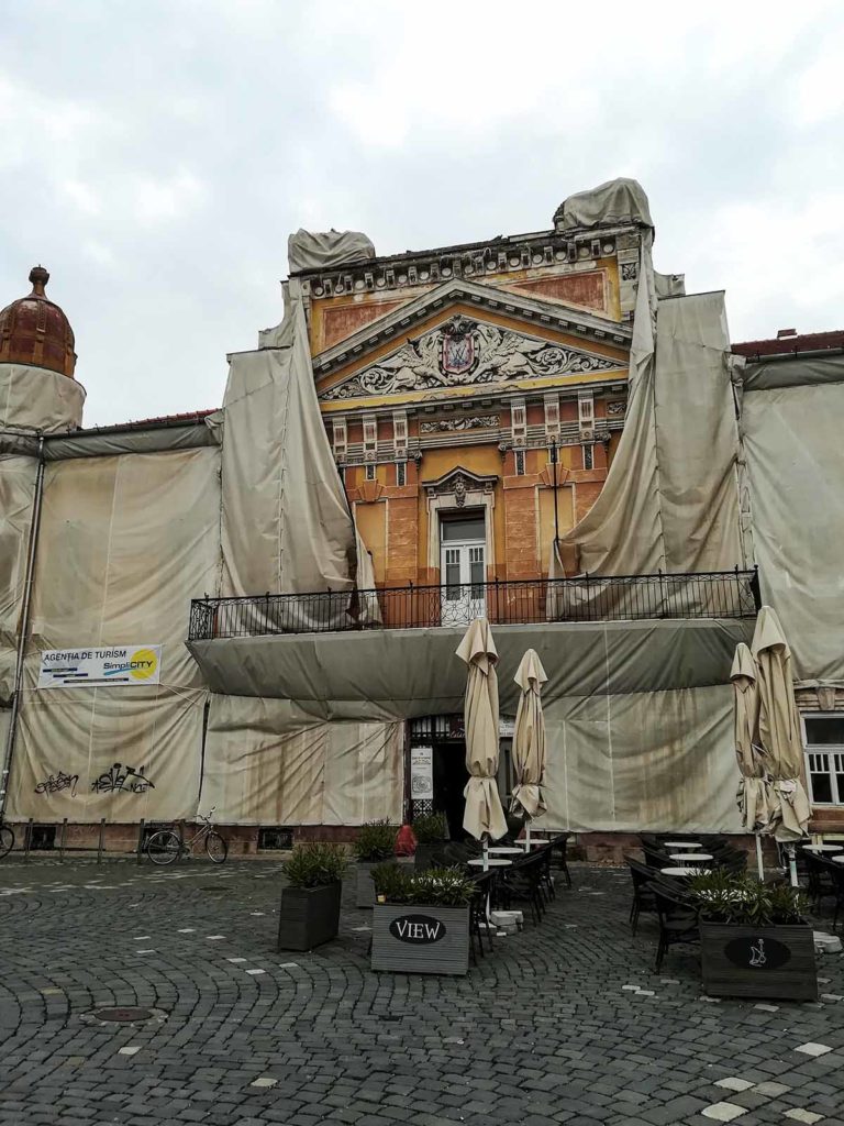 A old, orange building wrapped in large building linen.